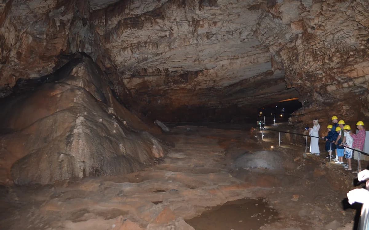 Tour visitors beside natural rock formations inside Vjetrenica Cave