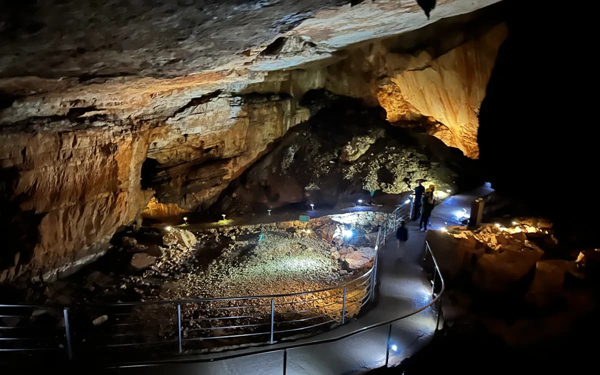 A lit visitor walkway and dramatic limestone interior inside Vjetrenica Cave near Ravno