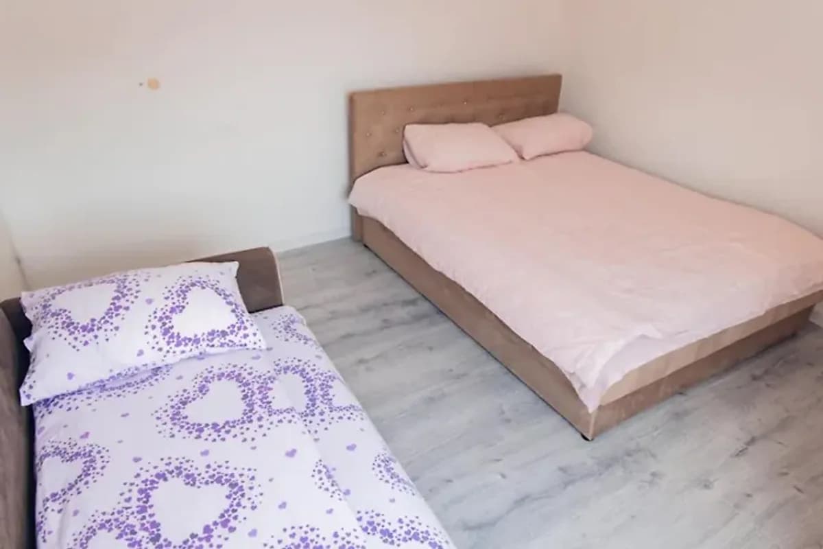 Apartman Marina Foča bedroom with light pink double bed and a smaller patterned single bed