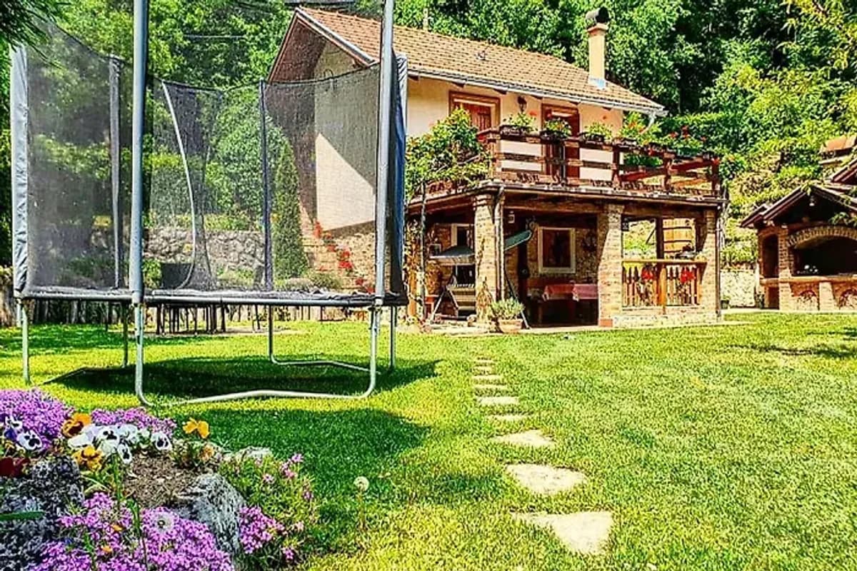 Banja Luka house Casa Rustica wooden vacation house with covered porch and trampoline in green garden