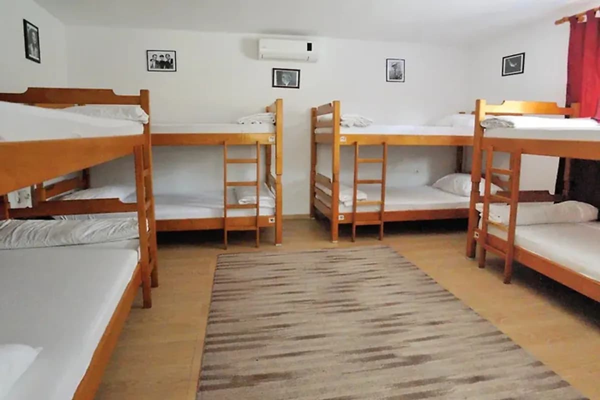 Hostel David Mostar dormitory with wooden bunk beds, rugs and pale walls