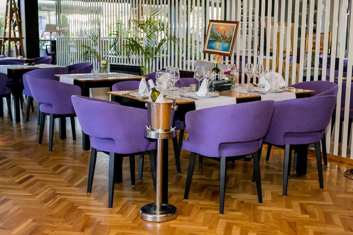 Purple dining chairs and prepared restaurant tables at Hotel Emporium in Bihać