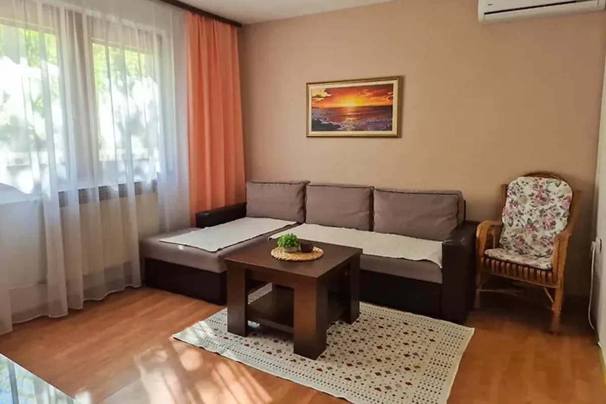 Spago Green Oasis Konjic living room with gray sofa, small wooden coffee table and pink curtains