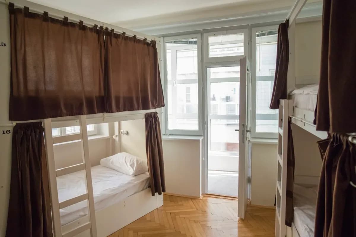 Bunk bed dormitory with brown curtains and bright windows at The Good Place Hostel in Sarajevo